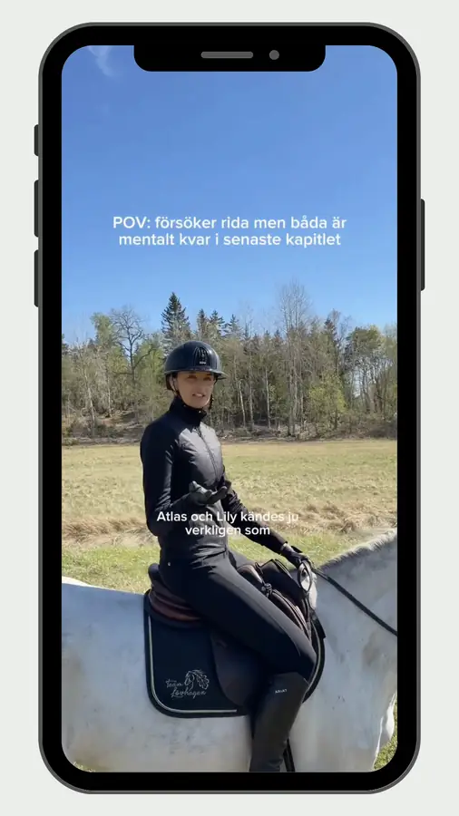 Melina rider på en vit häst utomhus